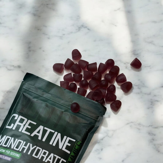 a pouch of nootra creatine gummies opened with gummies spread out on a marble counterttop